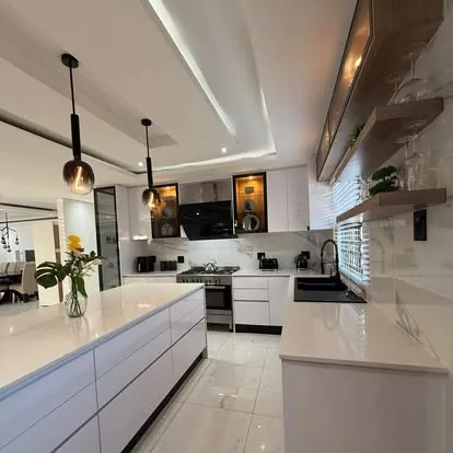 White kitchen with long island and pendant lights