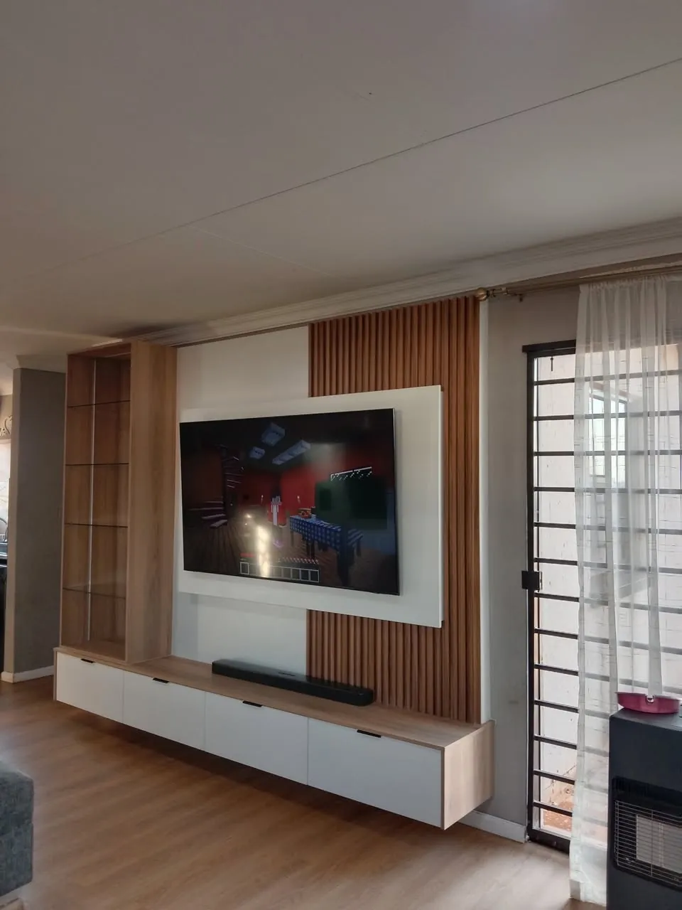 White TV wall unit with oak slats and floating shelf