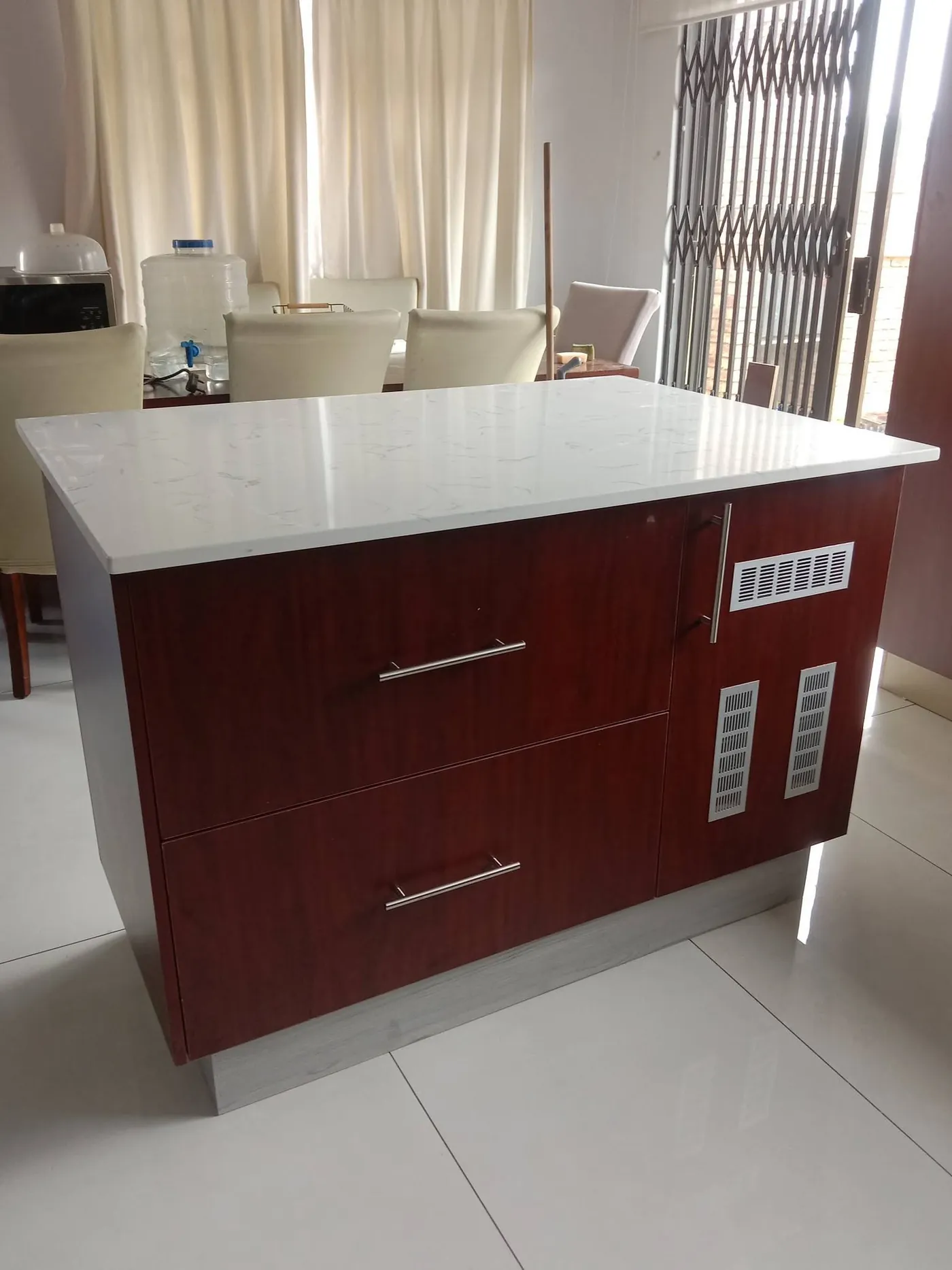 Kitchen island with mahogany-tone drawers and white marble-look top