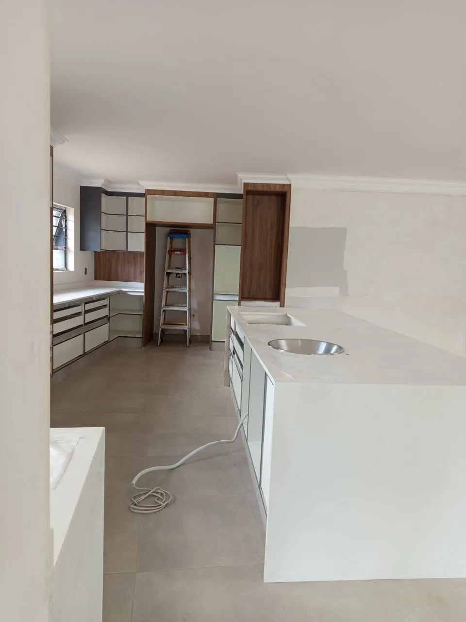 Kitchen install in progress with walnut tall units and white island